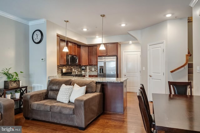 kitchen with appliances with stainless steel finishes, a peninsula, light stone counters, and open floor plan
