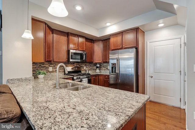 kitchen featuring brown cabinetry, a peninsula, light stone counters, appliances with stainless steel finishes, and backsplash