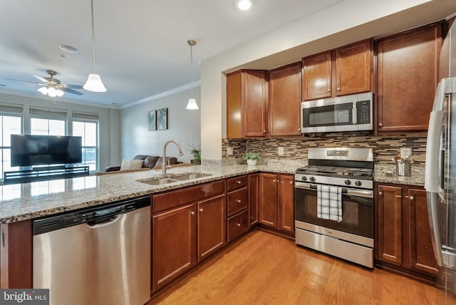 kitchen featuring crown molding, a sink, light wood-style floors, stainless steel appliances, and tasteful backsplash
