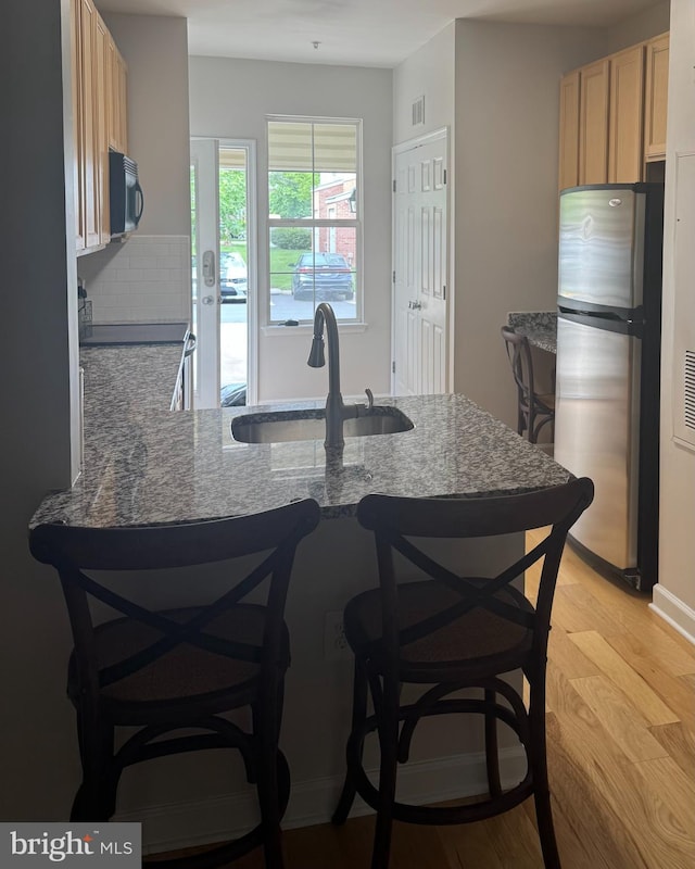 42429 Rockrose Sq, Brambleton, VA 20148 - kitchen with freestanding refrigerator, a sink, black microwave, light wood-style flooring, and light brown cabinetry