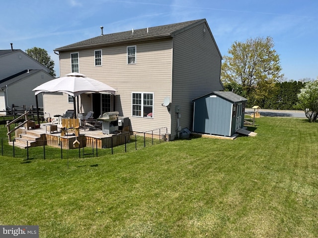 rear view of property with a storage shed, a lawn, a deck, an outbuilding, and fence