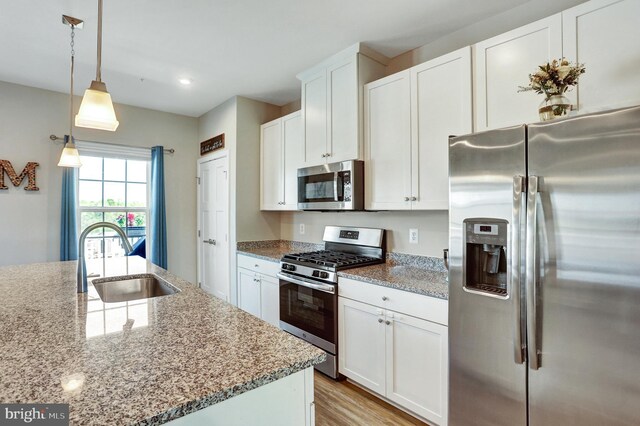 kitchen featuring light stone counters, a sink, white cabinets, and stainless steel appliances