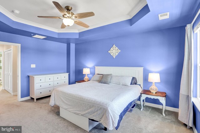 bedroom with light colored carpet, baseboards, visible vents, and a raised ceiling