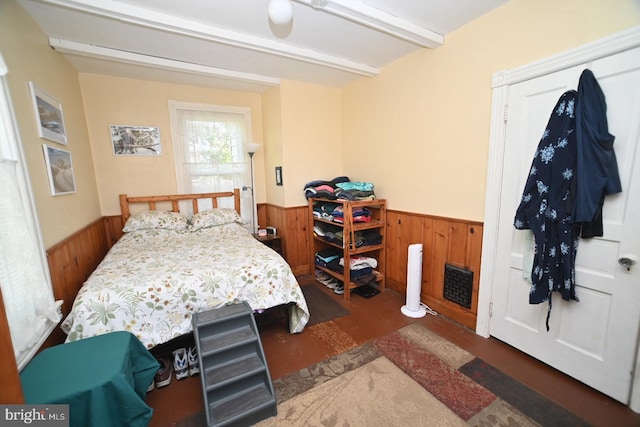 bedroom featuring wooden walls, wainscoting, and wood finished floors