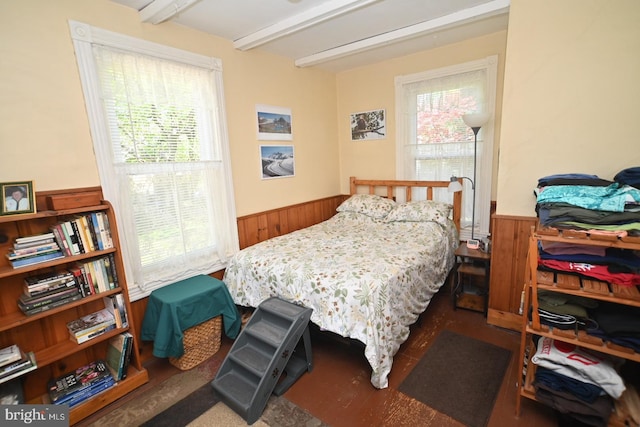 bedroom featuring wooden walls, beamed ceiling, and wainscoting