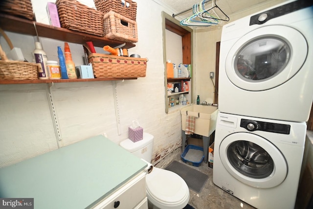 clothes washing area featuring laundry area, stacked washer and dryer, and a sink