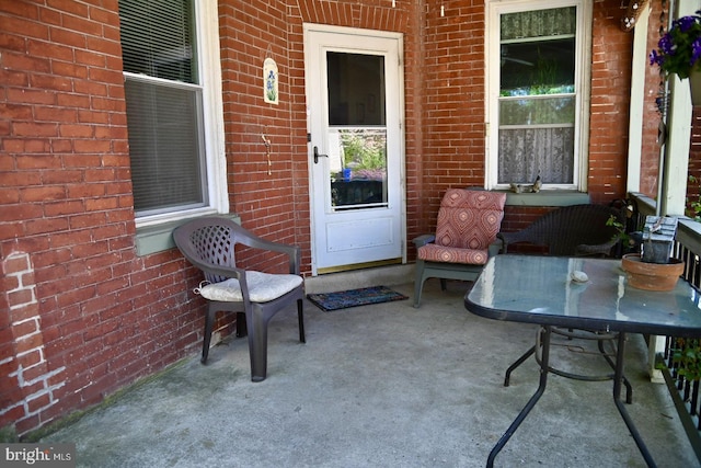 view of exterior entry with brick siding and a patio area