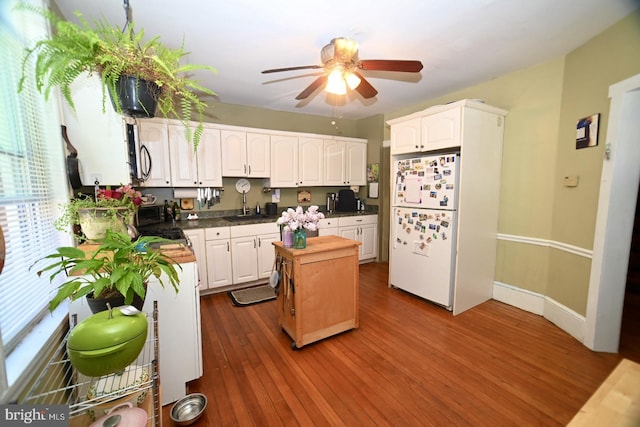 kitchen featuring a kitchen island, a ceiling fan, a sink, freestanding refrigerator, and dark wood-style floors