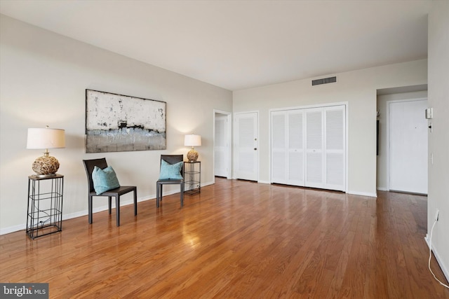living area featuring baseboards, wood finished floors, and visible vents