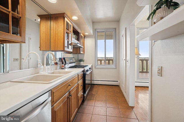 kitchen with baseboard heating, light countertops, brown cabinets, a sink, and stainless steel appliances