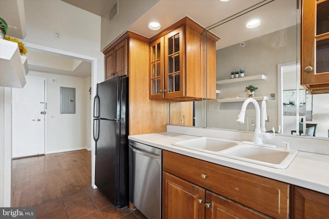 kitchen with stainless steel dishwasher, freestanding refrigerator, brown cabinetry, light countertops, and a sink