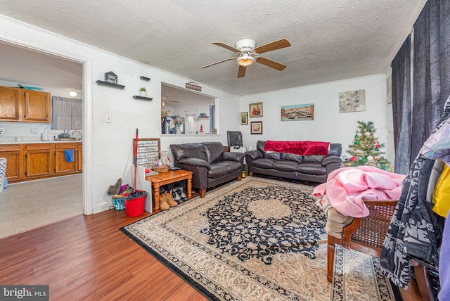 living area featuring a textured ceiling, ceiling fan, and wood finished floors