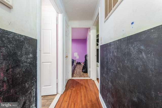 hall with ornamental molding, a textured ceiling, and wood finished floors