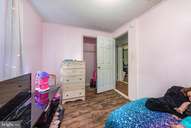 bedroom with a textured ceiling and wood finished floors