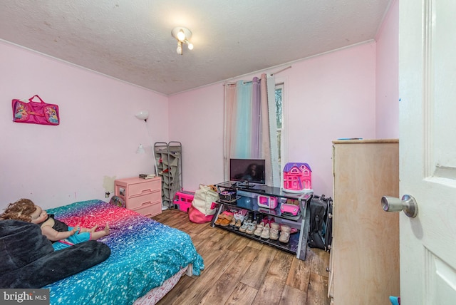bedroom with a textured ceiling and wood finished floors