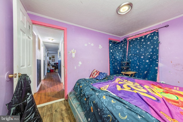 bedroom featuring crown molding, a textured ceiling, and wood finished floors