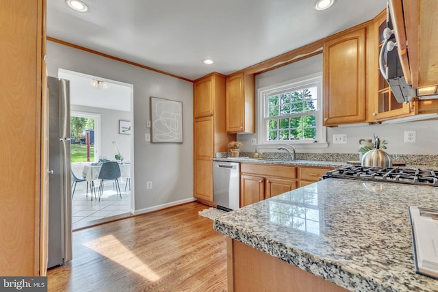 kitchen with appliances with stainless steel finishes, plenty of natural light, light wood-type flooring, light stone counters, and recessed lighting