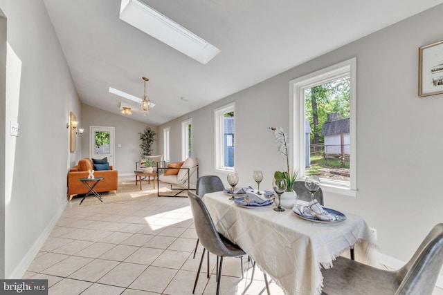 dining space featuring a chandelier, a skylight, vaulted ceiling, light tile patterned flooring, and baseboards