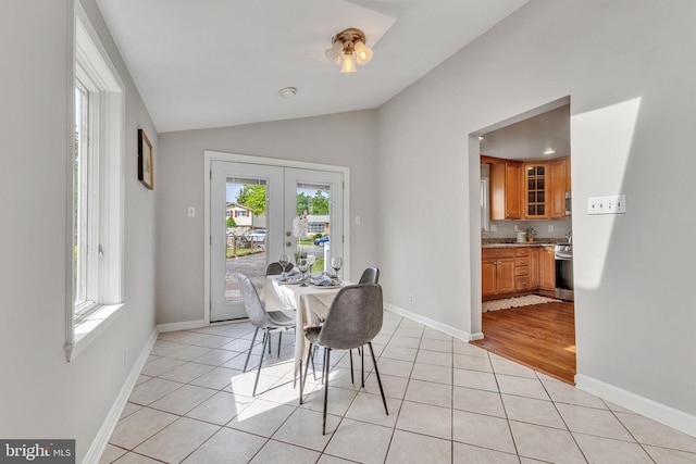 dining room with french doors, lofted ceiling, light tile patterned floors, and baseboards