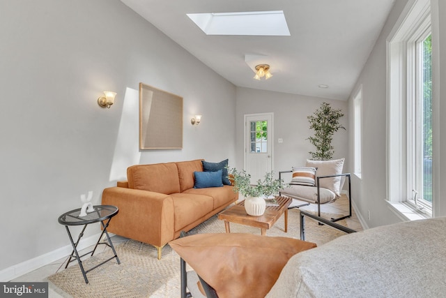living area with lofted ceiling, a skylight, baseboards, and light tile patterned floors