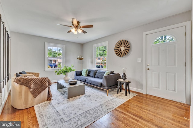 living area featuring a ceiling fan, light wood-style floors, and baseboards