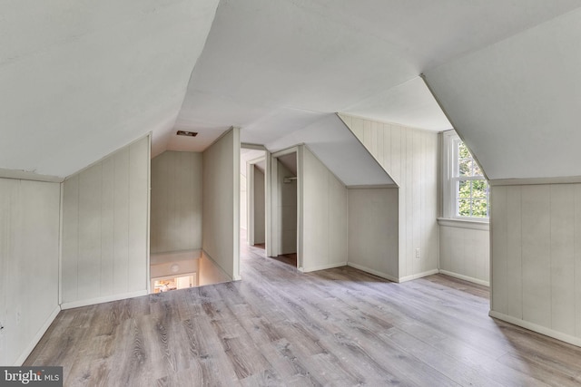 additional living space with wood finished floors, lofted ceiling, wooden walls, and baseboards
