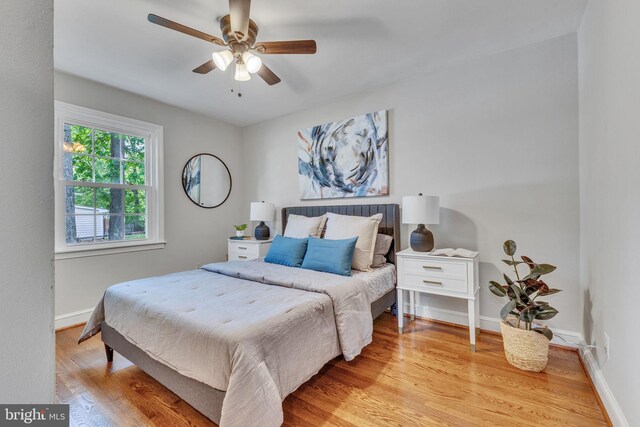 bedroom with light wood finished floors, baseboards, and ceiling fan