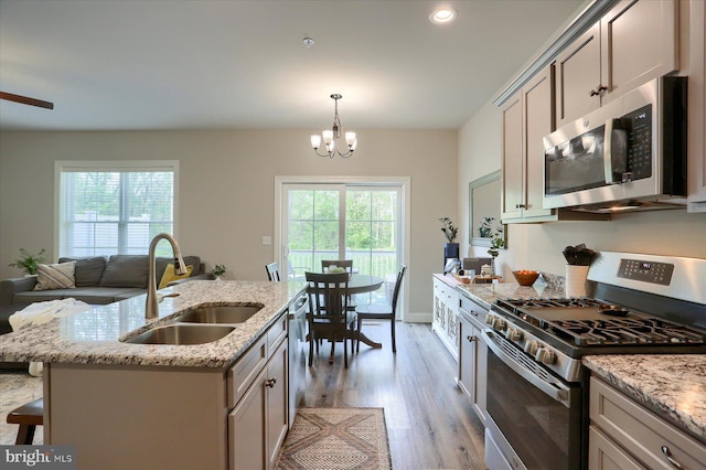 kitchen featuring a kitchen bar, light stone countertops, a sink, light wood-style floors, and stainless steel appliances