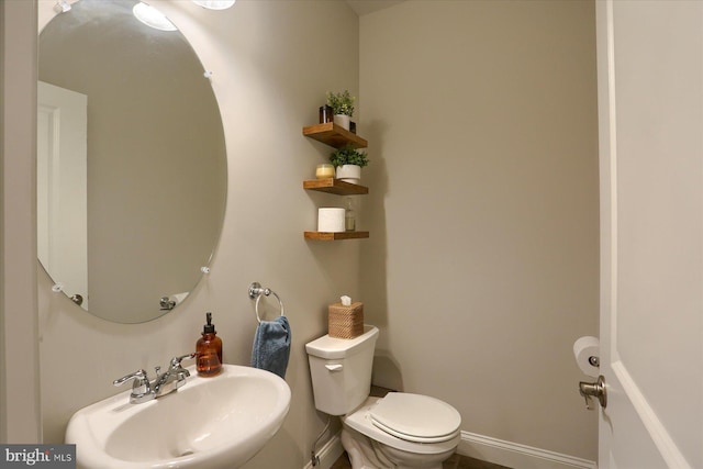 bathroom featuring baseboards, a sink, and toilet