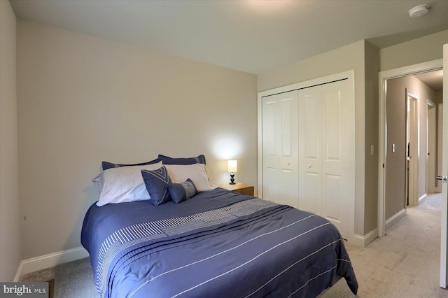 bedroom with baseboards, light colored carpet, and a closet