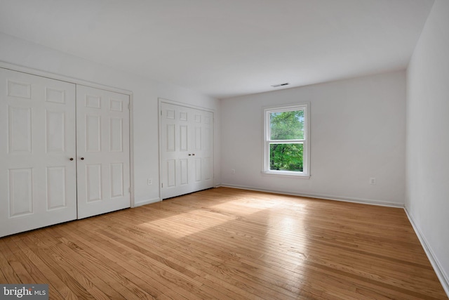 2407 Mare Ln, Oakton, VA 22124 - unfurnished bedroom with two closets, light wood finished floors, and baseboards