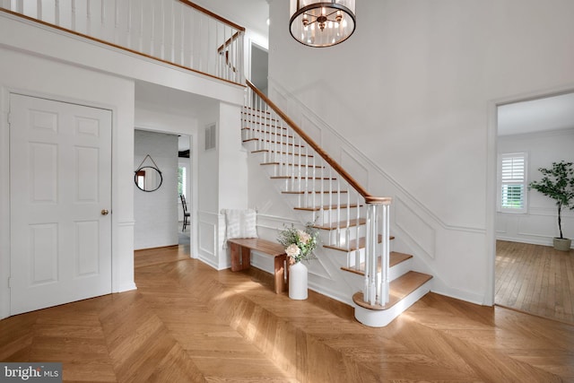 2407 Mare Ln, Oakton, VA 22124 - staircase featuring a decorative wall, a chandelier, a towering ceiling, and a wainscoted wall