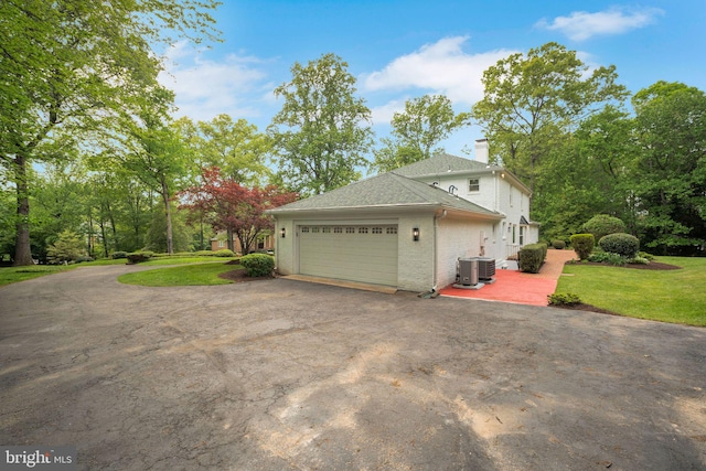 2407 Mare Ln, Oakton, VA 22124 - view of side of home featuring central AC unit, a garage, asphalt driveway, a chimney, and a yard