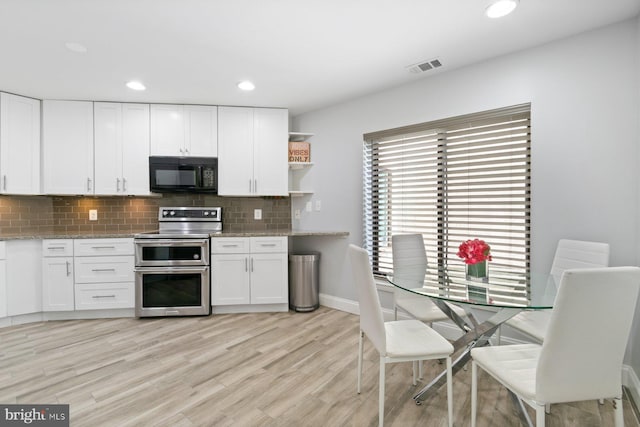 kitchen featuring double oven range, visible vents, black microwave, and white cabinetry