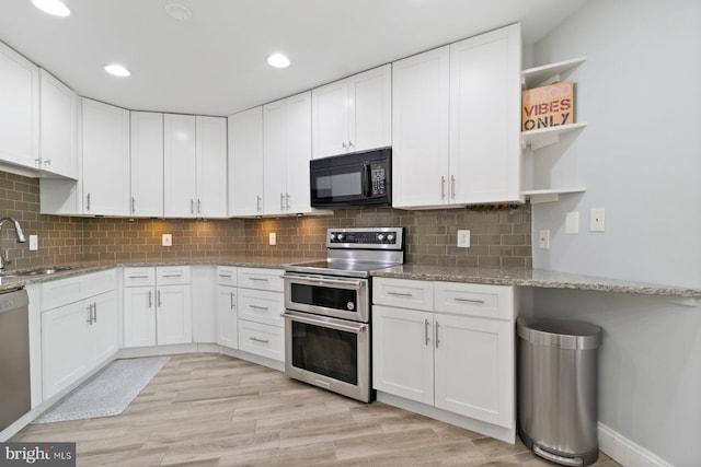 kitchen featuring open shelves, white cabinets, a sink, stainless steel appliances, and light stone countertops