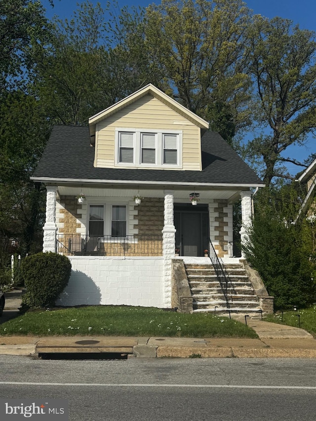 bungalow-style home featuring covered porch, stairway, a shingled roof, and stone siding