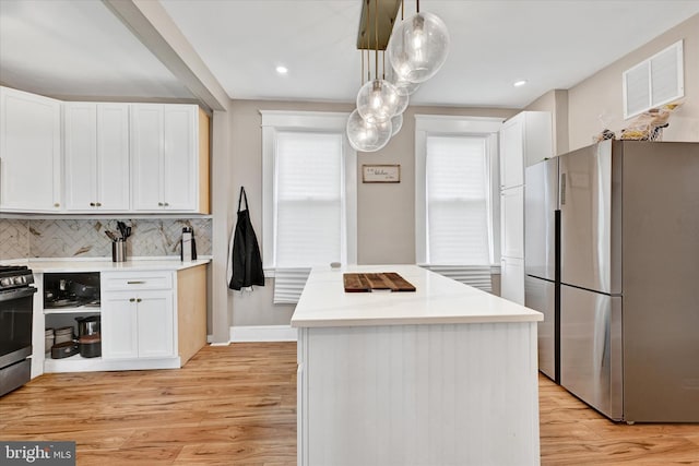 kitchen with a kitchen island, visible vents, appliances with stainless steel finishes, light countertops, and white cabinetry