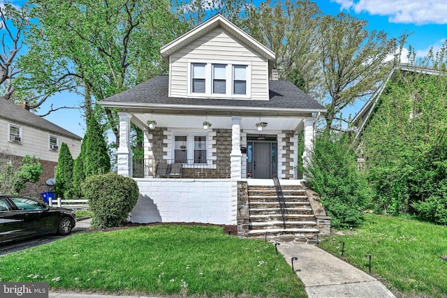 bungalow-style house with a porch, stairway, a shingled roof, and a front lawn