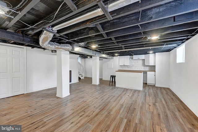 below grade area with baseboards, stairs, and light wood finished floors