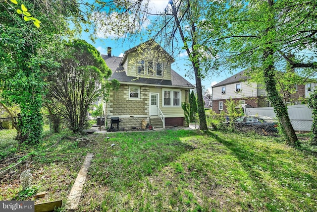 back of property featuring a fenced backyard, roof with shingles, and entry steps