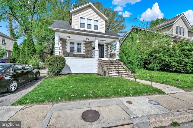 bungalow with covered porch, stairs, and a front lawn