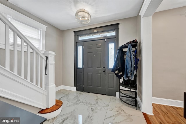 entryway with baseboards, marble finish floor, a notable chandelier, and stairway