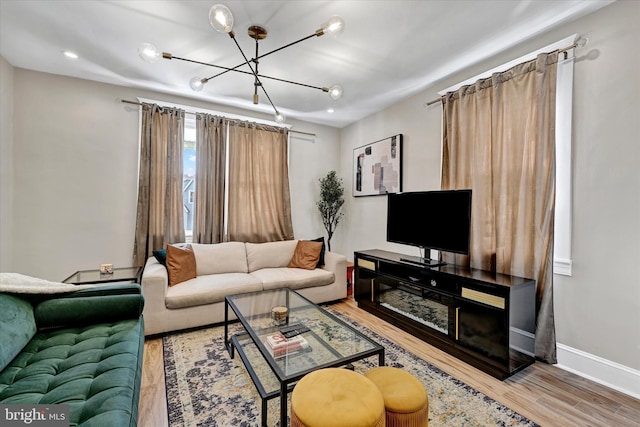 living area with baseboards, a notable chandelier, and wood finished floors
