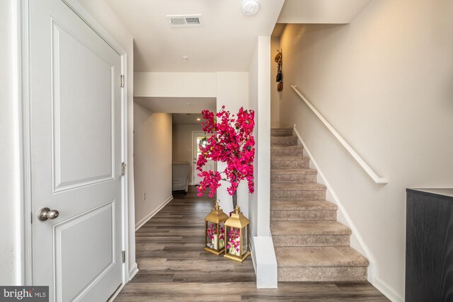 stairs featuring baseboards, wood finished floors, and visible vents