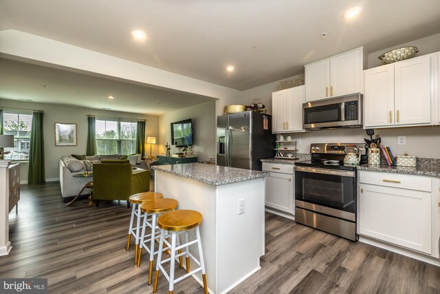 kitchen with open floor plan, dark wood-style flooring, a kitchen island, and stainless steel appliances