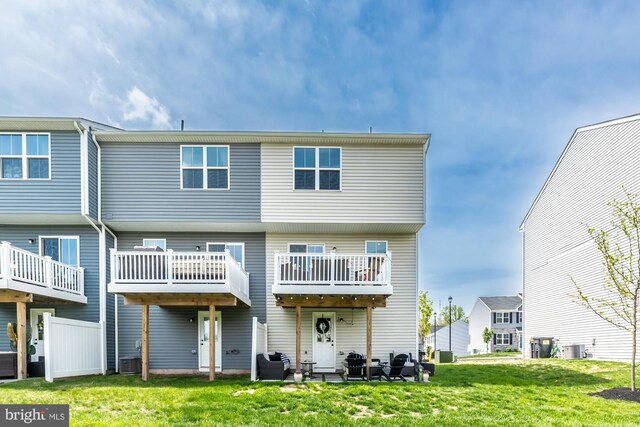 back of house with central AC unit and a yard