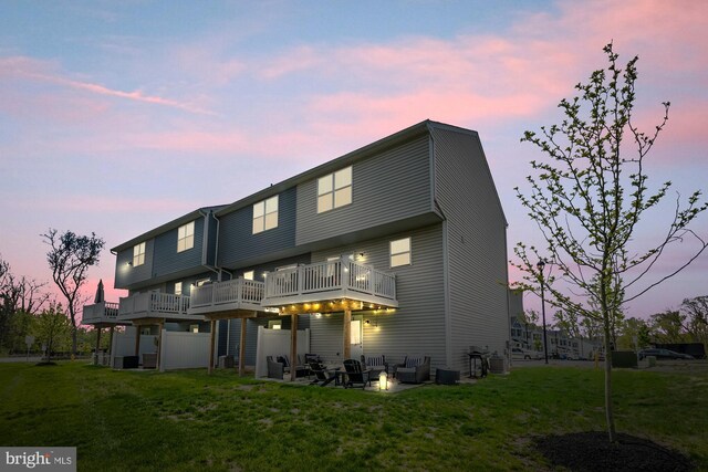 back of house at dusk featuring a lawn and an outdoor fire pit