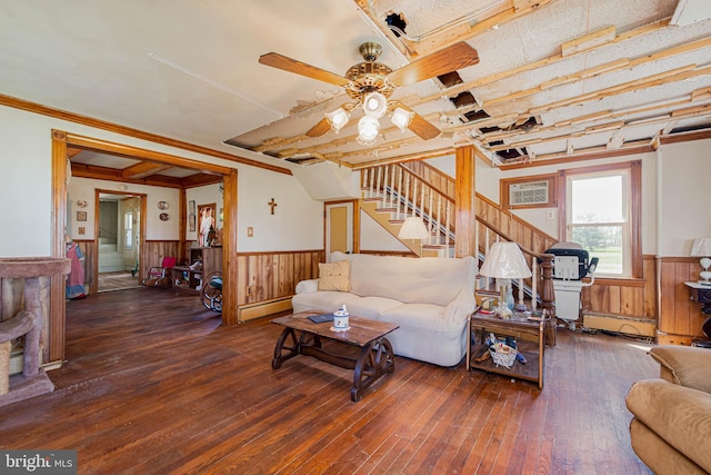 living room with stairway, a baseboard heating unit, wood-type flooring, a ceiling fan, and wainscoting