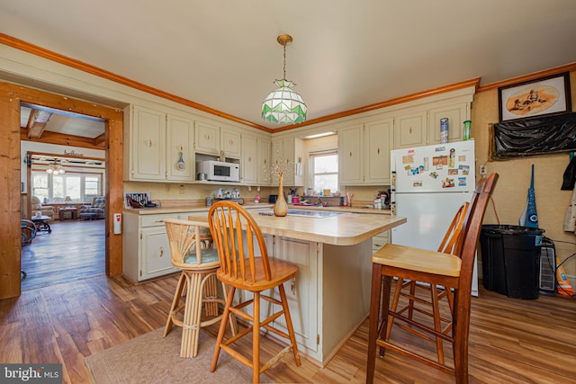 kitchen with light wood finished floors, a kitchen breakfast bar, white appliances, a center island, and light countertops