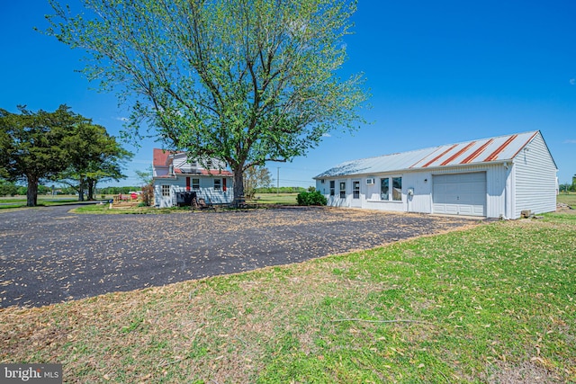 view of front of house featuring driveway, board and batten siding, a front lawn, and metal roof